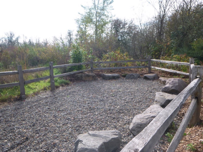 Group gathering area with large decorative boulders to sit on – loose gravel surface – wood railing
